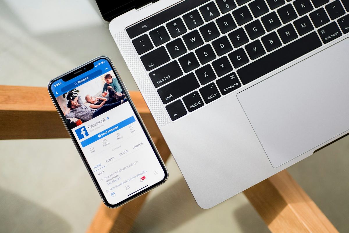 Dizüstü bilgisayarın yanında Facebook açık akıllı telefon